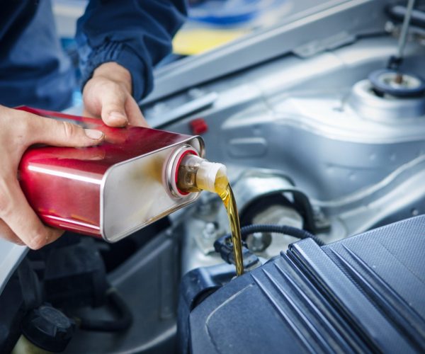 Mechanic changing engine oil on car vehicle.